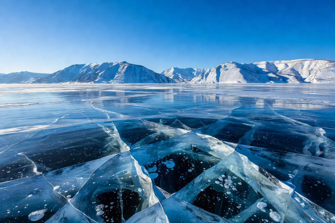Glace transparente du lac Baïkal en hiver avec fissures bleues sous la surface gelée